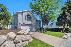 View of front facade with concrete driveway, a garage, and stone siding