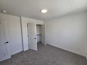 Unfurnished bedroom with dark carpet, a closet, and a textured ceiling