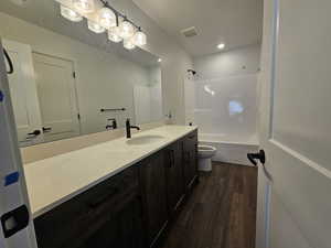 Bathroom featuring wood finished floors, vanity, and bathtub / shower combination