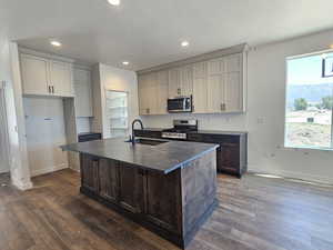 Kitchen featuring appliances with stainless steel finishes, dark countertops, dark wood finished floors, recessed lighting, and tasteful backsplash