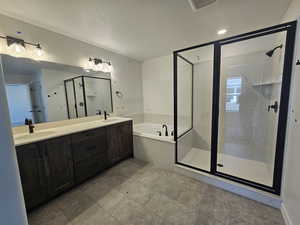 Bathroom with a bath, a shower stall, double vanity, a textured ceiling, and tile patterned flooring