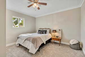 Primary bedroom featuring ornamental molding, light colored carpet, and a ceiling fan