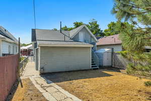 Back of property featuring a partially fenced backyard, roof with shingles, and a storage shed