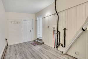 Laundry room with exit to backyard with wood type finished floors.