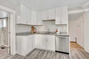Kitchen with dishwasher, white cabinets, and light wood-style flooring