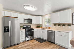 Kitchen featuring appliances with stainless steel finishes, white cabinets, and a textured ceiling