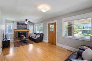 Living room with a tile fireplace, hardwood / wood-style floors, and ceiling fan