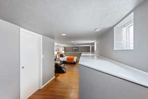 Hall with wood finished floors and recessed lighting