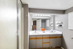 Full bath featuring double vanity and a shower with door
