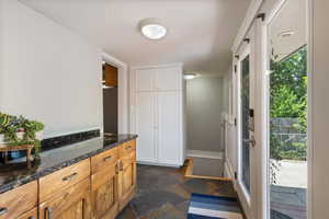 Kitchen with dark stone finish flooring, dark stone counters, and white cabinetry