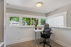 Carpeted home office featuring baseboards