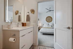 Bathroom featuring vanity, connected bathroom, a ceiling fan, and wood finished floors