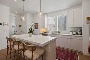Kitchen featuring light wood-style floors, a kitchen bar, tasteful backsplash, recessed lighting, and light countertops