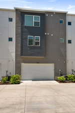 View of front facade featuring driveway, a garage, and stucco siding