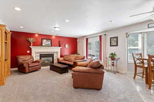 Living room with light colored carpet, recessed lighting, a glass covered fireplace, a ceiling fan, and a textured ceiling