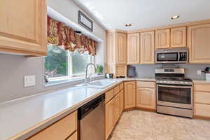 Kitchen with stainless steel appliances, light brown cabinetry, light countertops, and recessed lighting