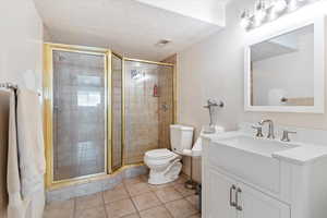 Bathroom featuring vanity, a stall shower, tile patterned flooring, and a textured ceiling