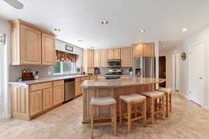 Kitchen featuring appliances with stainless steel finishes, light brown cabinetry, a kitchen breakfast bar, a center island, and recessed lighting