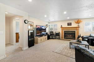Living area featuring recessed lighting, light carpet, a glass covered fireplace, and a textured ceiling