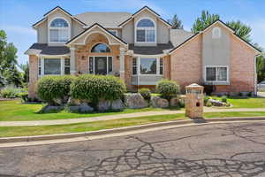 Traditional-style home featuring brick siding, a front lawn, stucco siding, and a shingled roof