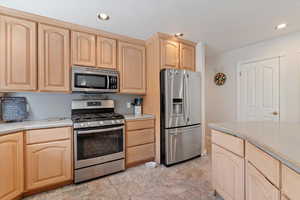 Kitchen featuring appliances with stainless steel finishes, light brown cabinetry, light countertops, and recessed lighting