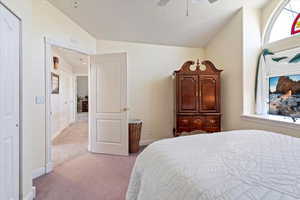 Bedroom with light colored carpet, vaulted ceiling, and ceiling fan