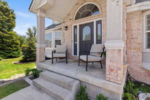 Property entrance featuring covered porch and brick siding