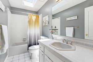 Full bath with a skylight, vanity, and shower / bath combination with curtain