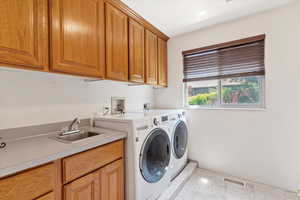 Washroom featuring light marble finish floors, cabinet space, and washer and clothes dryer