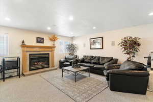 Carpeted living room featuring a glass covered fireplace, recessed lighting, and a textured ceiling