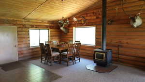 Dining room with wooden ceiling, a wood stove, and log walls