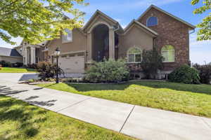 View of front of property with driveway, a front lawn, stucco siding, and brick siding