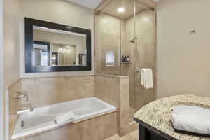 Full bath with a shower stall, vanity, and a garden tub