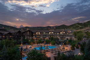 Pool at dusk featuring a mountain view, a community pool, and a patio area
