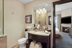 Ensuite bathroom featuring a glass covered fireplace and vanity