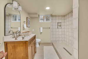 Full bathroom featuring tile patterned flooring, vanity, and a tile shower