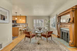 Living room with a tile fireplace and light wood-type flooring