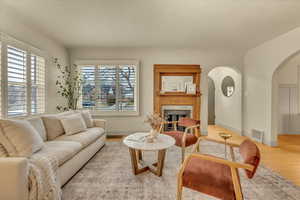 Living room with arched walkways, wood finished floors, and a fireplace