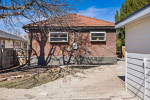 View of side of home featuring a tile roof and brick siding