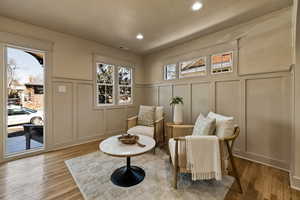 Living area featuring a decorative wall, wood finished floors, recessed lighting, and wainscoting