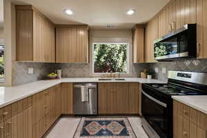 Kitchen featuring stainless steel appliances, light stone countertops, decorative backsplash, recessed lighting, and light tile patterned floors