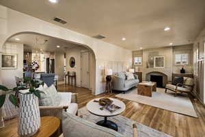 Living room featuring arched walkways, wood-type flooring, recessed lighting, and a chandelier