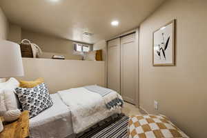 Bedroom with a closet, light carpet, and recessed lighting