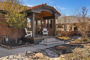 Doorway to property featuring covered porch and brick siding