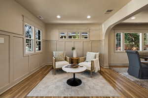Living area with a decorative wall, wood finished floors, plenty of natural light, arched walkways, and recessed lighting