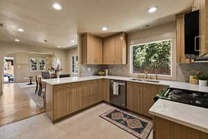 Kitchen featuring stainless steel dishwasher, a peninsula, arched walkways, recessed lighting, and decorative backsplash