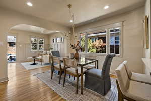 Dining space with arched walkways, wood finished floors, and recessed lighting