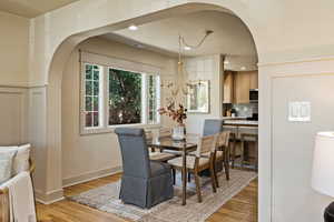 Dining area featuring arched walkways, light wood-style flooring, and recessed lighting