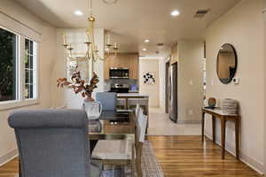 Dining room with recessed lighting, light wood-style flooring, and a chandelier