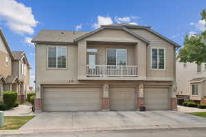 View of property with an attached garage, stucco siding, brick siding, and concrete driveway